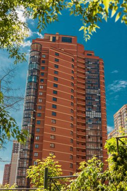 Turuncu tuğlalardan yapılmış tuğlalar mavi gökyüzünün altında ve parkın yanında.