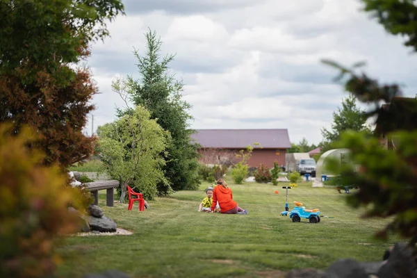 mom talking to her little son sitting in a green meadow