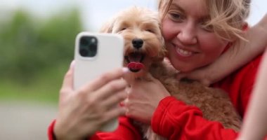 Novosibirsk Rusya 06.13.2021 Kadın küçük bir Maltipu köpeğiyle selfie çekiyor