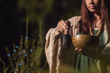 Yogi kadın ormanda oturuyor ve müzik kaseleri oynuyor.