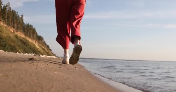 Kobieta Jasnoczerwonych Spodniach Biegnie Wzdłuż Plaży Piasku Zachodzącym Słońcu — Wideo stockowe