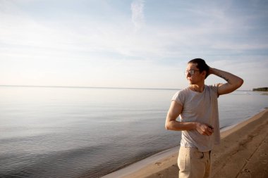 Bir adam kumsalda yürüyor ve güneşin tadını çıkarıyor.