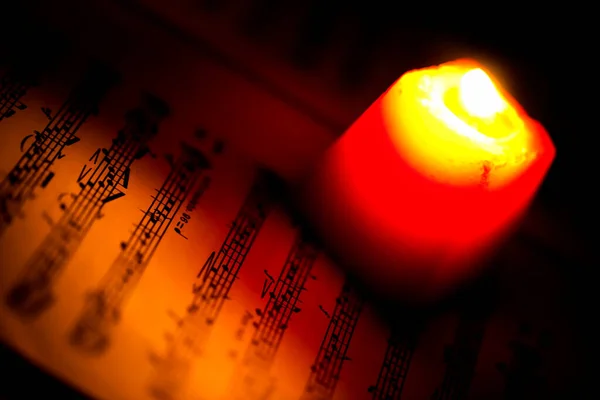 Kırmızı Mum Işığındaki Müzik Notaları Sayfası — Stok fotoğraf