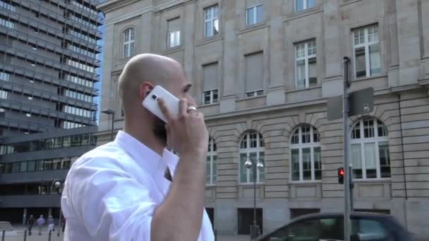 Hombre hablando con el teléfono celular en la ciudad cerca de las torres de tráfico y negocios — Vídeo de stock