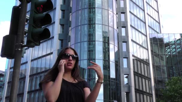 Mujer hablando con celular y torres de negocios en la ciudad — Vídeos de Stock