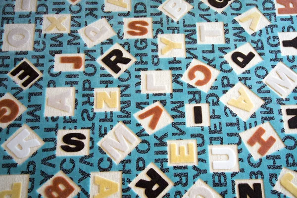 Alfabetos em uma superfície de tapete de tecido — Fotografia de Stock