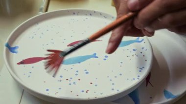 Seramik Stüdyosunda Fırçayla Balık desenli Tabağa Boya Taneleri Sıçratmak 