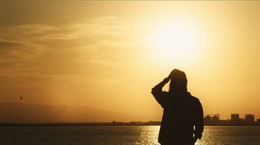 Yüksek kalite siluet bir fotoğraf dramatik bir günbatımı sırasında deniz kenarında gün batımını seyreden yalnız bir figürü gösteriyor. Sahne, duygu, yaşam tarzı, özgürlük ve sakin atmosferi yakalıyor ve seyahat, yaşam tarzı gibi ticari stok kullanımına uygun hale getiriyor.