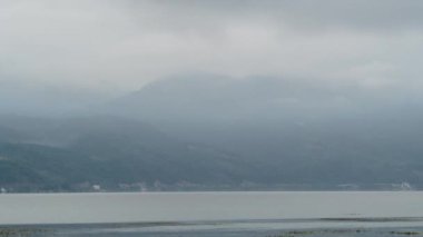 4k 'lik hızlandırılmış sis videosu, arka planda nehir ve dağ zirveleri olan kırsal bir dağ bölgesinde hareket ediyor.