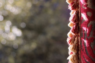 Pencereden dışarı bakan bahçenin görüntüsü, yan yana sıralanmış kalın ipekten perdeler. 