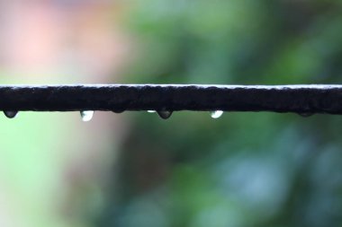 Bahçe arka planı metal çubuk damlayan yağmuru ve yumuşak yeşil arkaplanı gösteriyor