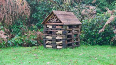 Çimlerin üzerinde ahşap çatılı ve arkasında ağaçlar olan ahşap bir dükkan. 