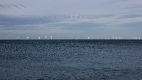 Windpark am Horizont auf See mit dunkelblauem Meer unten und blassblauem Himmel oben — Stockfoto