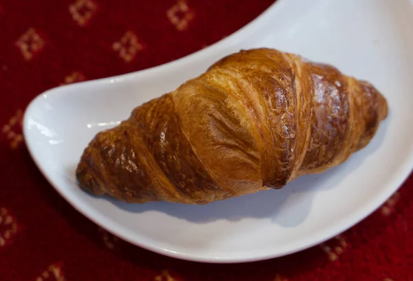 Croissant único no prato branco em forma de crescente com espaço de cópia — Fotografia de Stock