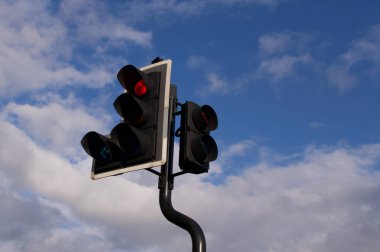 Koyu mavi bulutlu gökyüzüne karşı kırmızı ışıkta trafik ışığı