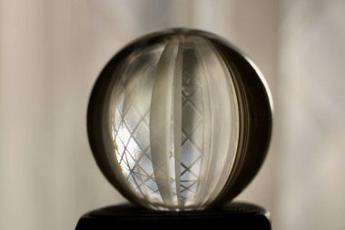 Pencereyi yansıtan cam top ve yumuşak gri arkaplan perdeleri