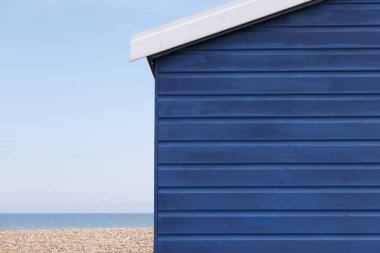 Koyu mavi sahil kulübesi, ufuk çizgisi ve plaj manzaralı.