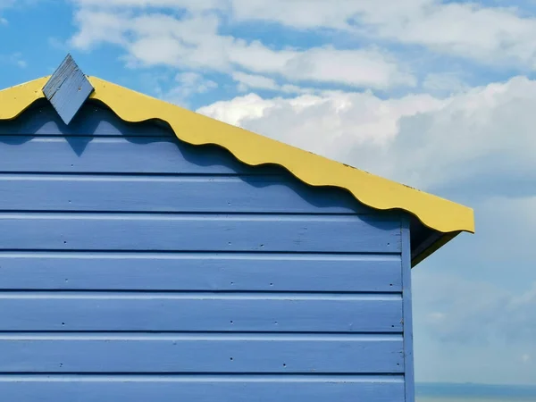 Cabana de praia de madeira azul e amarela contra céu nublado azul com copyspace — Fotografia de Stock