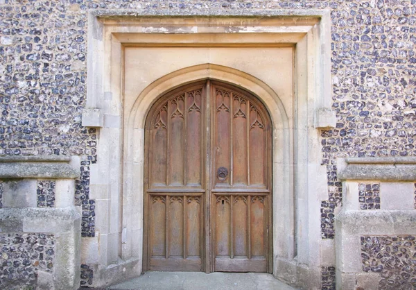 Régi fából készült ajtó a keresztény templom ágyazott kovakő fal — Stock Fotó