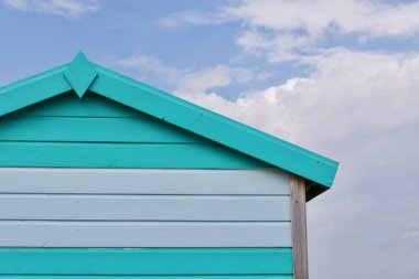 Plaj kulübesi parlak floresan su ile boyanmış ve bulutlu gökyüzüne karşı beyaz