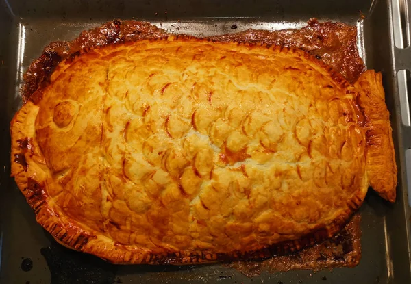 Ev yapımı altın rengi hamur işi balık turtası ve tepside pullar.