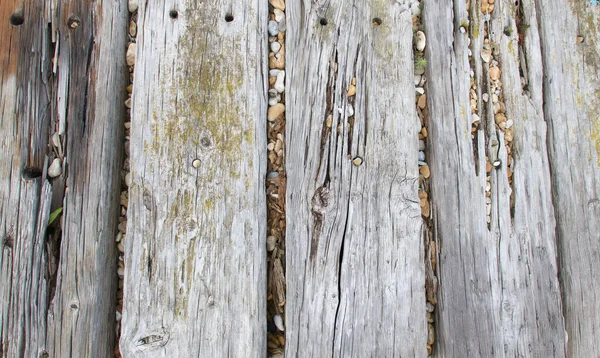 Velhas tábuas de madeira desgastadas com pedras em brechas — Fotografia de Stock