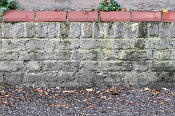 Parede de tijolo resistente ao intemperismo cinza velho com telhas de terracota no topo — Fotografia de Stock