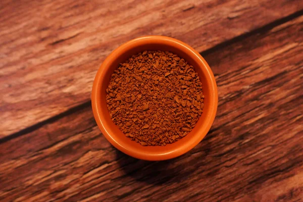 Malá terakotová mísa z hnědé instantní kávy granule na dřevěném pozadí — Stock fotografie