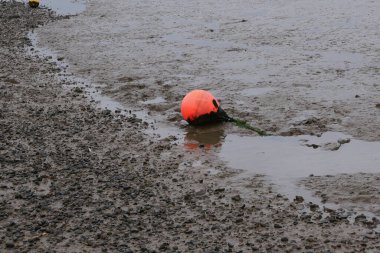 Çamurda duran ipe bağlı parlak turuncu floresan şamandıra.