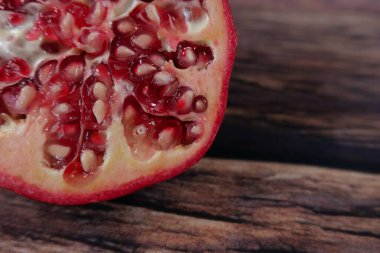 Tohum detaylarını gösteren sulu kırmızı sulu nar ahşap masada duruyor.