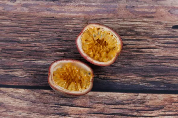 Deux moitiés de fruits de la passion coupés debout sur une table en bois grossier — Photo