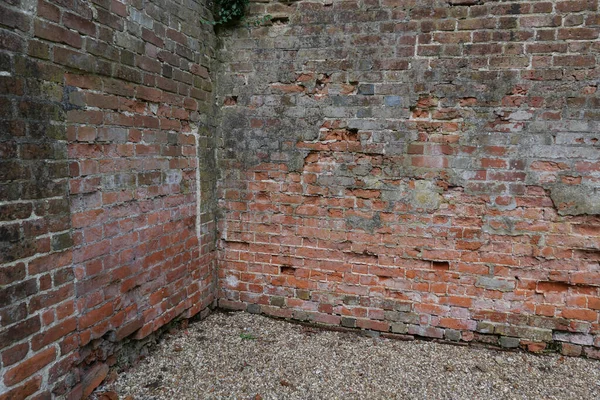 Oude verweerde bakstenen tuinhoek met grind op de grond — Stockfoto