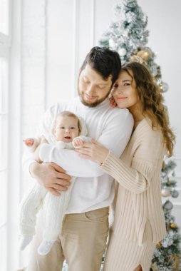Küçük bir çocukla güzel bir aile Noel için dekore edilmiş bir evin penceresinde duruyor.