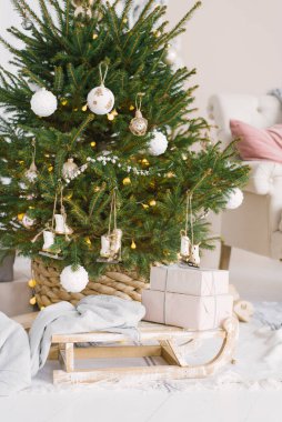 Noel kızağında hediyeler ve oturma odasındaki Noel ağacının yanında yeni yıl için süslenmiş bir battaniye.