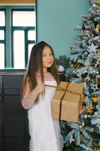 Πορτρέτο Του Κοριτσιού Μπροστά Από Χριστουγεννιάτικο Δέντρο Κρατώντας Δώρο Κοιτάζοντας — Φωτογραφία Αρχείου