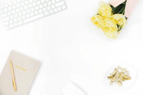 スタイリッシュな女性用デスク オフィスデスク コンピュータのあるワークスペース 黄色のチューリップの花束 クリップボード ノートとボールペンのメモ帳 薄い白の背景に女性のファッションアクセサリー 平面上面 — ストック写真