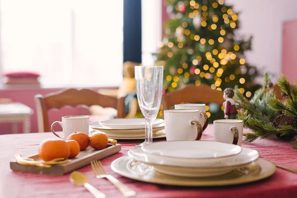 ホワイトプレート シャンパングラス クリスマスのためのお祝いのディナーの提供にみかん クリスマスツリーライトの背景にクリスマスの前夜 — ストック写真