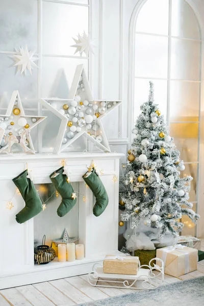 Oturma odasının altın ve gümüş tonlarıyla süslenmiş bir Noel dekoru. Güzel dekore edilmiş büyük bir Noel ağacı şöminenin yanındaki odada duruyor..