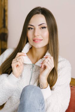 Profesyonel makyajlı, yün kazak giymiş güzel bir kadın. Minimalist biçim ve pastel renkler.