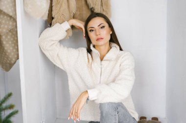 Güzel genç bayan, dolapların yanında, yerde oturuyor.