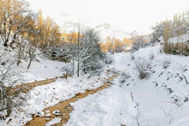 Özbekistan 'daki karlı dağ manzarası. Uzaktaki Chimgan dağı, güneşle aydınlanıyor. Chimgansay Nehri