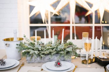 Dekorasyonlu, mumlu ve fenerli güzel bir masa. Oturma odası çelenkler ve bir Noel ağacı ile süslenmiş. Şenlikli atmosfer