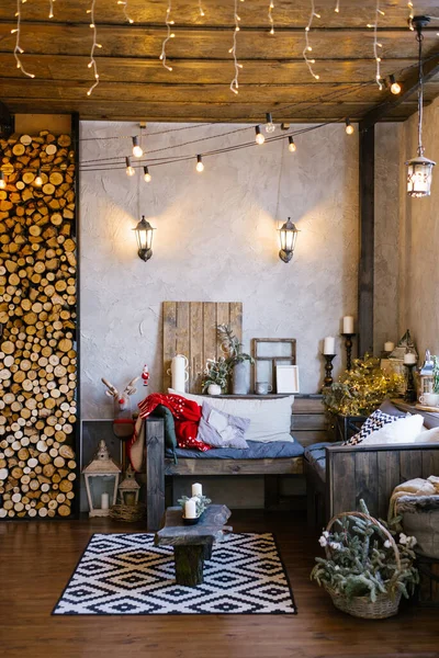 The interior of a country house, decorated for Christmas and New Year. Sofa with pillows and retro light bulbs in the living room