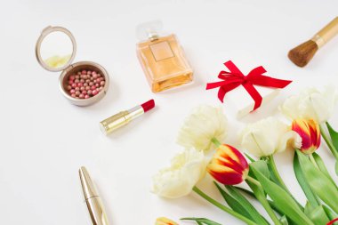 Kırmızı hediye paketinde kırmızı ve sarı laleler, kozmetik ürünler ve kopyalama alanı olan beyaz bir arkaplanda hediye. Sevgililer Günü ya da Anneler Günü için tebrik kartı. Tarz sahibi blogger düz yatıyordu