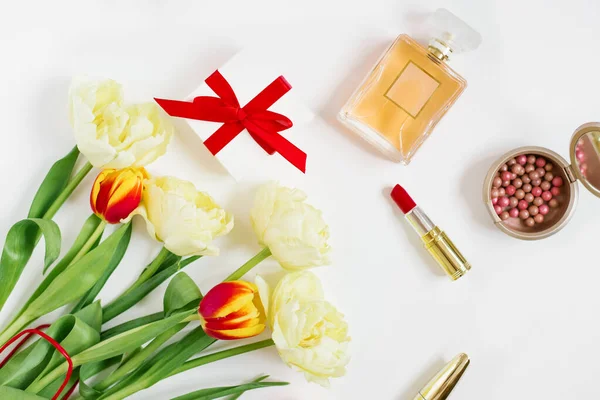 Femenine is a composition of women\'s work space with gifts for Mother\'s Day and Valentine\'s Day. Cosmetics and a bouquet of tulip flowers. Spring top view.