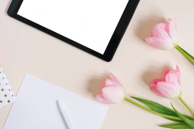 Düz düz görünüm modeli: dijital tablet ve bej arkaplanda pembe laleler. Boşluğu ve düzlüğü kopyala. Bahar için blog konsepti, Anneler Günü, Sevgililer Günü