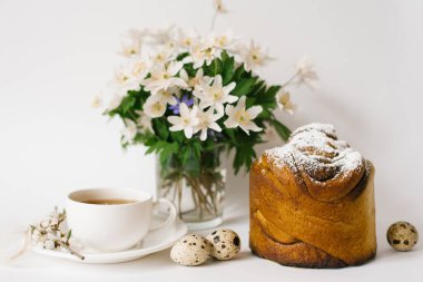 Paskalya kartı. Bir pasta, bir fincan çay, vazoda çuha çiçekleri ve arka planda bıldırcın yumurtası.