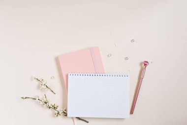 İçinde beyaz elma çiçekleri olan boş bir defter kağıdı, pembe bir defter ve bej arka planda pembe bir kalem. Bir blog için bahar kavramı