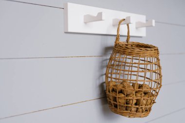 Mutfağın minimalist iç tasarımı gri İskandinav duvarında asılı beyaz bir askı ve bir sepet cevizle süslenmiş.