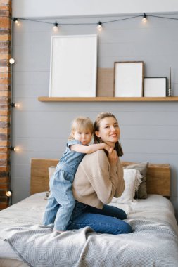 Genç anne iki yaşındaki kızına yatakta sarılıyor.